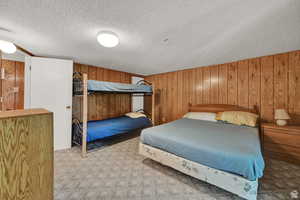 Bedroom with wood walls, carpet flooring, and a textured ceiling