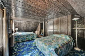 Bedroom with vaulted ceiling, wood walls, and wood ceiling