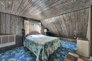 Bedroom featuring wooden walls, wood ceiling, lofted ceiling, carpet, and radiator