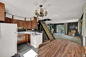 Kitchen with sink, white appliances, a chandelier, and a textured ceiling