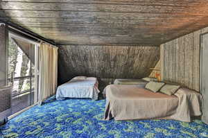 Carpeted bedroom featuring wood ceiling and vaulted ceiling