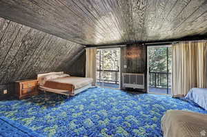 Carpeted bedroom featuring access to exterior, heating unit, and vaulted ceiling