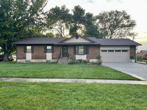 Ranch-style house featuring a garage and a front yard