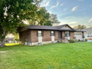 Ranch-style home featuring a garage and a front lawn