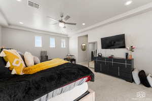 Primary Bedroom featuring light colored carpet, ceiling fan, and a raised ceiling