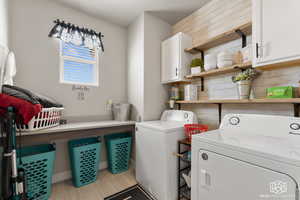 Washroom featuring cabinets, wood walls, and separate washer and dryer