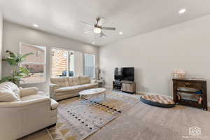 Carpeted living room with a textured ceiling and ceiling fan