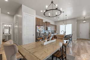 Dining room with a textured ceiling, sink, a notable chandelier, and light hardwood / wood-style floors