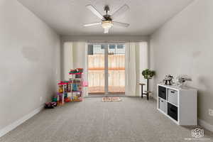 Loft area/living room with a textured ceiling, carpet, and ceiling fan