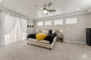 Primary Bedroom with ceiling fan, a raised ceiling, and carpet floors