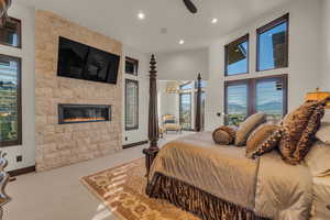 Bedroom featuring a fireplace, light colored carpet, multiple windows, and ceiling fan