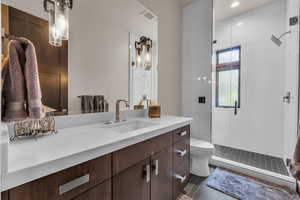 Bathroom featuring tile patterned flooring, vanity, a shower with door, and toilet