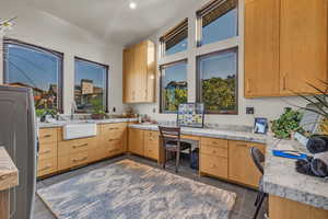 Kitchen with stainless steel refrigerator, sink, dark tile patterned floors, light brown cabinetry, and built in desk