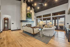 Living room with a wealth of natural light, a stone fireplace, and high vaulted ceiling