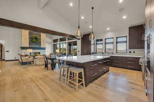 Kitchen featuring beam ceiling, a center island, light hardwood / wood-style floors, and dark brown cabinetry