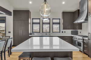 Kitchen with a center island, sink, wall chimney range hood, tasteful backsplash, and high end stainless steel range