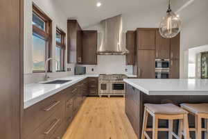 Kitchen featuring tasteful backsplash, stainless steel appliances, sink, wall chimney range hood, and pendant lighting