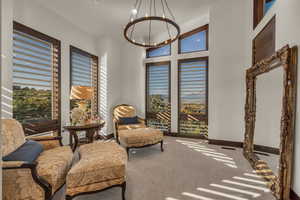 Sitting room featuring carpet floors, a high ceiling, and a notable chandelier