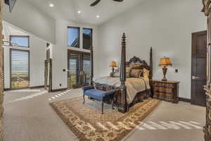 Bedroom featuring ceiling fan, french doors, a towering ceiling, light colored carpet, and access to outside