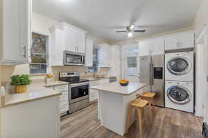 VIRTUALLY STAGED - FRIDGE AND WASHER/DRYER EXCLUDED - Kitchen featuring white cabinets, stainless steel appliances, and stacked washer / dryer