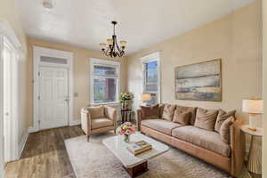 VIRTUALLY STAGED -Living room with an inviting chandelier and hardwood / wood-style flooring