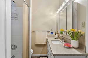 VIRTUALLY STAGED - Full bathroom with vanity, toilet, wood-type flooring, and tiled shower / bath