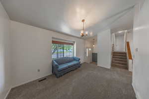 Unfurnished room with a textured ceiling, a notable chandelier, and carpet floors