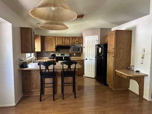 Kitchen with stainless steel appliances, kitchen peninsula, a breakfast bar area, and dark hardwood / wood-style flooring