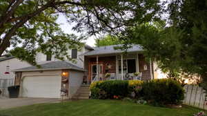 Split level home featuring a front lawn, a garage, and a porch