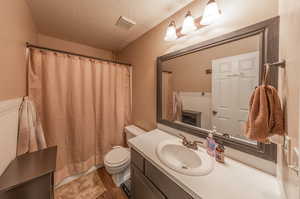 Bathroom featuring hardwood / wood-style floors, toilet, a textured ceiling, and vanity