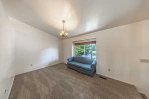 Unfurnished room with lofted ceiling, a chandelier, and carpet floors