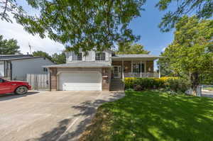 Tri-level home featuring a garage, a front yard, and a porch