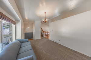 Living room featuring carpet flooring, vaulted ceiling, and an inviting chandelier