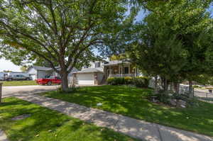 View of front of property featuring covered porch, a garage, and a front lawn