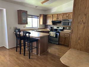 Kitchen with dark hardwood / wood-style floors, sink, kitchen peninsula, a kitchen breakfast bar, and stainless steel appliances