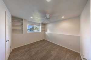 Carpeted empty room with a textured ceiling and ceiling fan