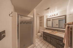 Bathroom featuring a textured ceiling, vanity, an enclosed shower, tile patterned flooring, and toilet