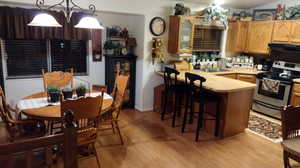 Kitchen featuring range hood, an inviting chandelier, light wood-type flooring, sink, and stainless steel range with electric cooktop