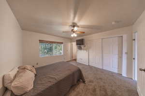 Carpeted bedroom with a textured ceiling and ceiling fan