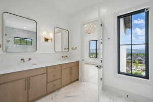 Bathroom featuring marble look tiles, a mountain view, double vanity, and plenty of natural light