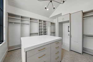 Spacious closet featuring a chandelier, light carpet, and high vaulted ceiling