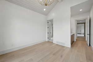 Unfurnished room featuring a chandelier, light wood-type flooring, recessed lighting, baseboards, and beam ceiling