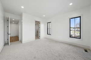 Unfurnished bedroom featuring light carpet, recessed lighting, baseboards, and ensuite bathroom