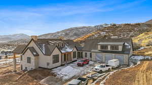 Snow covered rear of property featuring a mountain view and a garage