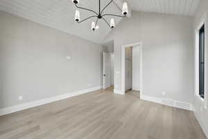 Unfurnished bedroom with light wood finished floors, a chandelier, baseboards, high vaulted ceiling, and wooden ceiling with exposed beams