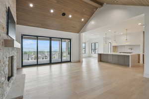 Unfurnished living room featuring high vaulted ceiling, a fireplace, light wood-type flooring, recessed lighting, and wood ceiling with exposed beams