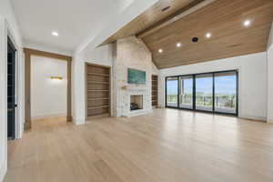 Unfurnished living room with baseboards, built in features, a stone fireplace, light wood-style floors, and recessed lighting