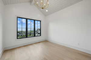 Unfurnished room with a chandelier, light wood-style flooring, high vaulted ceiling, beamed ceiling, and baseboards