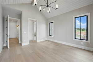 Empty room with light wood-type flooring, a chandelier, baseboards, high vaulted ceiling, and wood ceiling with exposed beams