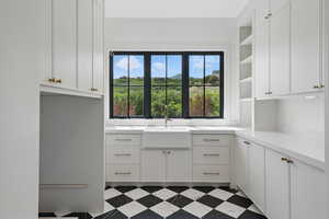 Kitchen featuring open shelves, a sink, white cabinets, and light countertops
